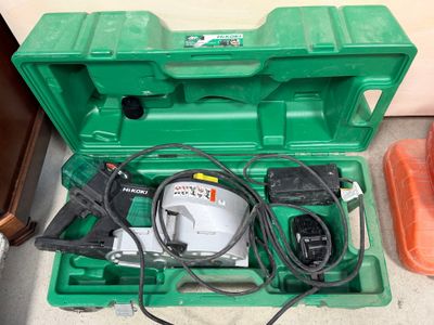 une boîte à outils verte posée par terre, contenant des outils