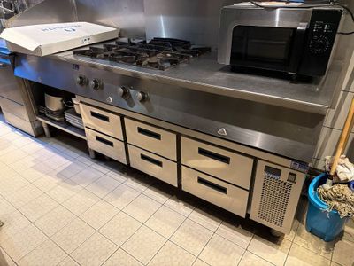 une cuisine équipée d'une cuisinière, d'un four, d'un micro-ondes et d'une boîte à pizza posée sur le plan de travail