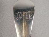 a silver spoon with a handle on a white surface