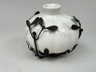 un vase blanc orné de feuilles noires
