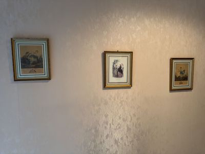 three framed pictures on the wall above a toilet