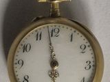 une montre à gousset en or suspendue à un mur blanc
