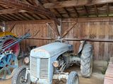 un vieux tracteur dans une grange, à côté d'autres machines agricoles