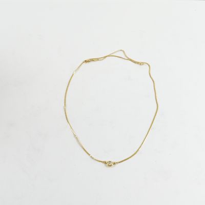 un bracelet à chaîne en or avec une breloque en forme de cœur sur fond blanc