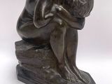 bronze sculpture of a man sitting on a rock with his head in his hands