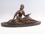 statue en bronze représentant une femme assise sur un rocher avec un chien