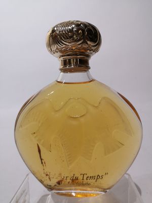 une photo d'un flacon de parfum posé sur une table transparente