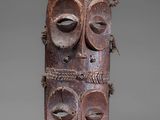 an old wooden mask with two faces and a rope around it