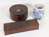 une petite boîte en bois et une tasse posées sur une surface blanche