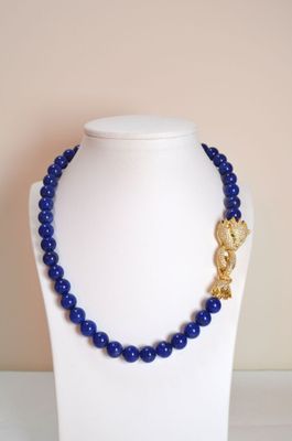 un gros plan d'un collier sur un mannequin, orné de perles bleues