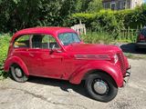 une voiture rouge garée sur un parking à côté d'un immeuble