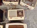 several old fashioned radio ' s are sitting on the floor