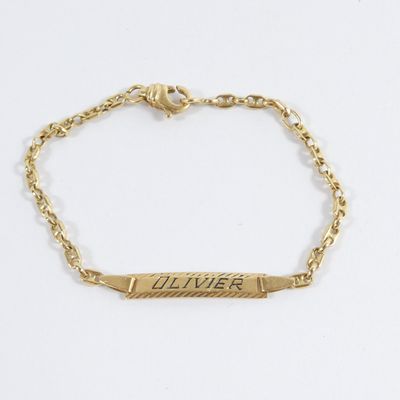 un gros plan sur un bracelet en or sur lequel est gravé un prénom