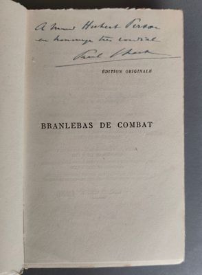 un livre ouvert, sur lequel on peut lire des notes manuscrites, posé sur une table