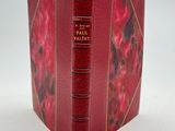 un vieux livre à la couverture rouge posé sur une table blanche