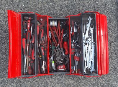 de nombreux outils dans une boîte rouge posée par terre