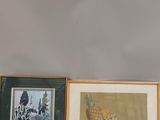 three framed pictures on a shelf above a bowl of fruit and a bowl of oranges