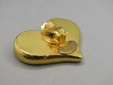 a gold heart shaped brooch with a coin on it