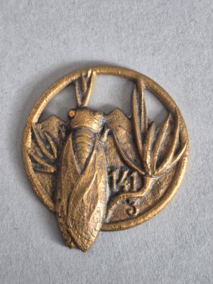 une image représentant un pendentif en forme d'insecte doré posé sur une surface blanche