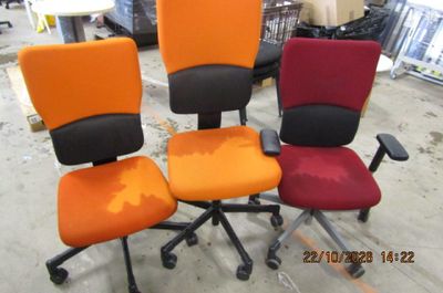Trois chaises de bureau sont alignées dans un entrepôt