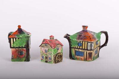 trois théières en céramique ornées de maisons, disposées les unes à côté des autres