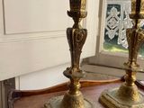 pair of antique brass candlesticks on a wooden table in front of a window