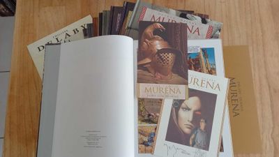 an open book sitting on top of a wooden table filled with magazines