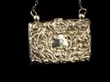 a silver purse with a pearl in it on a chain