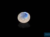 une pierre de lune blanche posée sur une surface noire dans l'obscurité