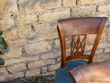 two wooden chairs sitting next to each other near a brick wall