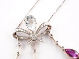 a silver necklace with a bow and a pink crystal