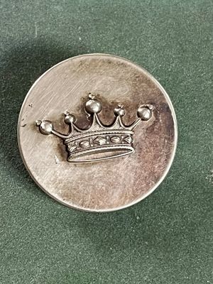 une pièce d'argent sur laquelle figure une couronne, posée sur un fond vert