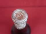 a small glass bottle with a lid on a red surface