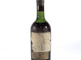 une vieille bouteille de vin posée sur une surface blanche