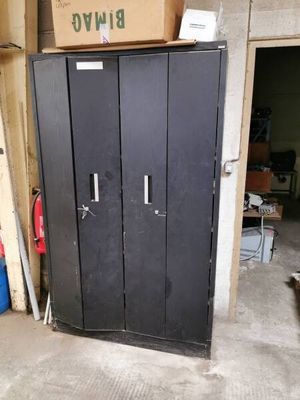 une armoire métallique noire dans un garage, sur laquelle est posée une boîte