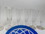 bottles and glasses are lined up on a table with a blue plate
