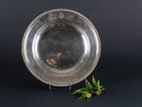 an antique silver plate with a flower on a black background
