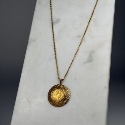 une pièce d'or suspendue à une chaîne en or, posée sur un socle en marbre