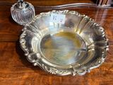 un plat en argent ancien posé sur une table en bois, à côté d'une bouteille en verre