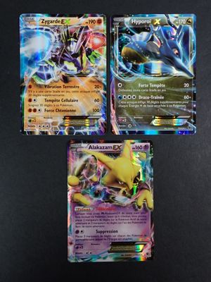 Trois cartes Pokémon sont posées sur une table