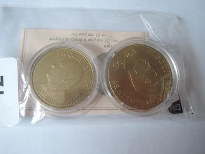 deux pièces d'or et d'argent dans des sachets en plastique posés sur une table