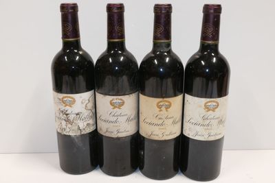 quatre bouteilles de vin sont alignées sur une surface blanche