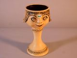 un petit vase orné d'un visage, posé sur une table