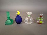 quatre vases en verre de couleurs différentes posés les uns à côté des autres sur une table