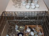 a metal basket filled with dishes and cups on a table