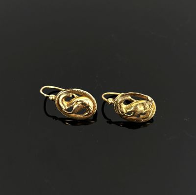 une image représentant une paire de boucles d'oreilles en or posées sur une surface noire