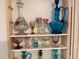 many glass vases on the shelves in this cabinet