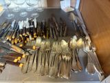 a lot of silverware on a table with wine glasses in the background