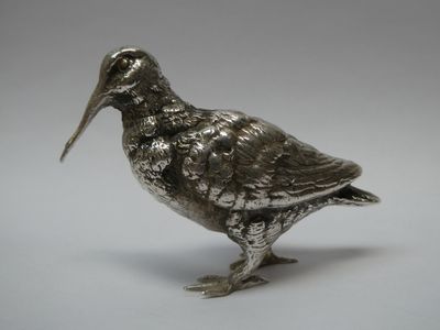 figurine d'oiseau en argent avec un long bec et de longues pattes