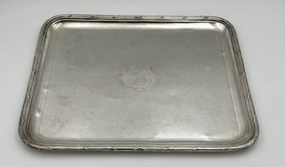 un plateau ancien en argent posé sur une table blanche, muni d'une poignée en argent